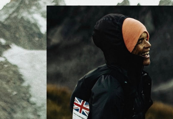 A person in an orange hat and black coat is laughing.