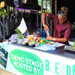 A chef leads a cooking demonstration from a stall as she's seasons a dish 