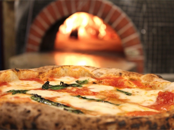 Pizza coming out of a wood fired oven.