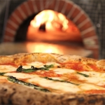 Pizza coming out of a wood fired oven.