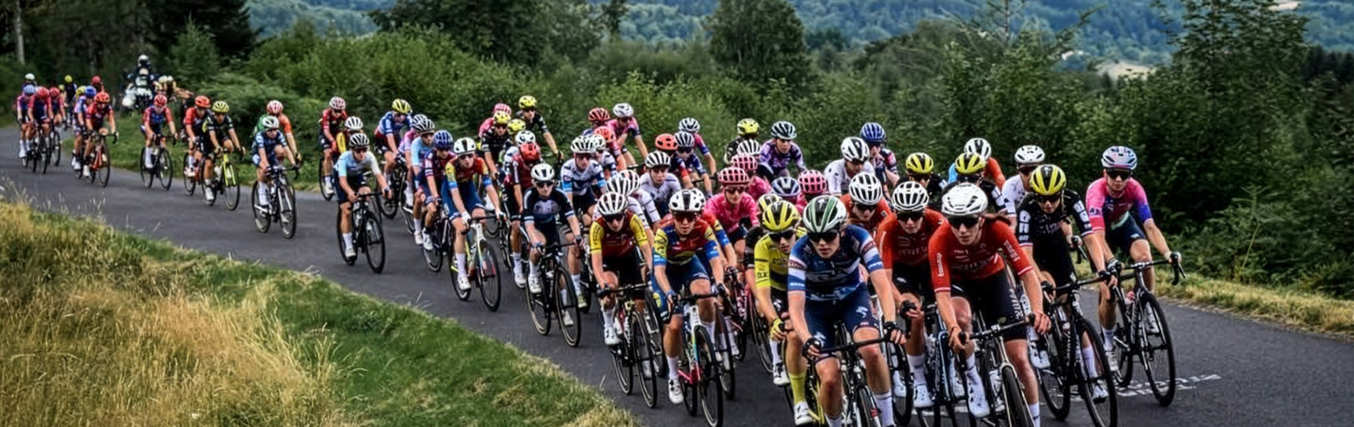A large group of female road cyclists cycle through the country side, as part of the Tour de France Femme avec Zwift.