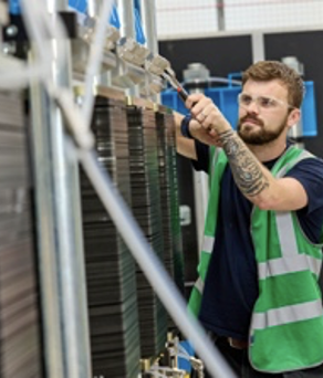 A man in a green high viz vest is working on a piece of machinery.