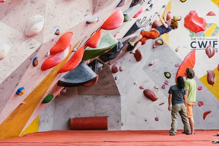 Friends watch a climber on an indoor bouldering wall at the Climbing Works, one of the indoor climbing walls mentioned in this article.