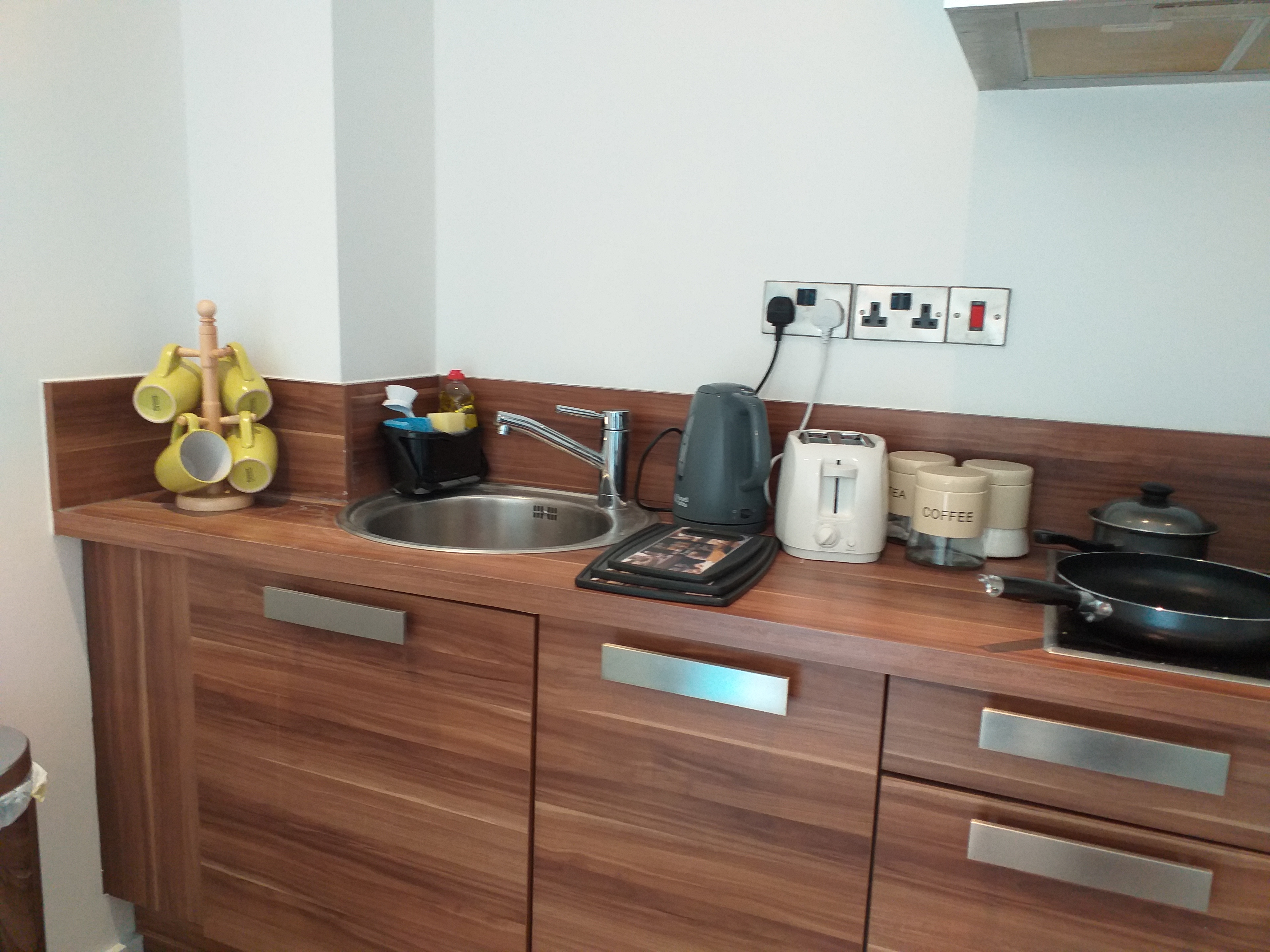Compact kitchenette with a kettle and tea and coffee making facilities on the counter.