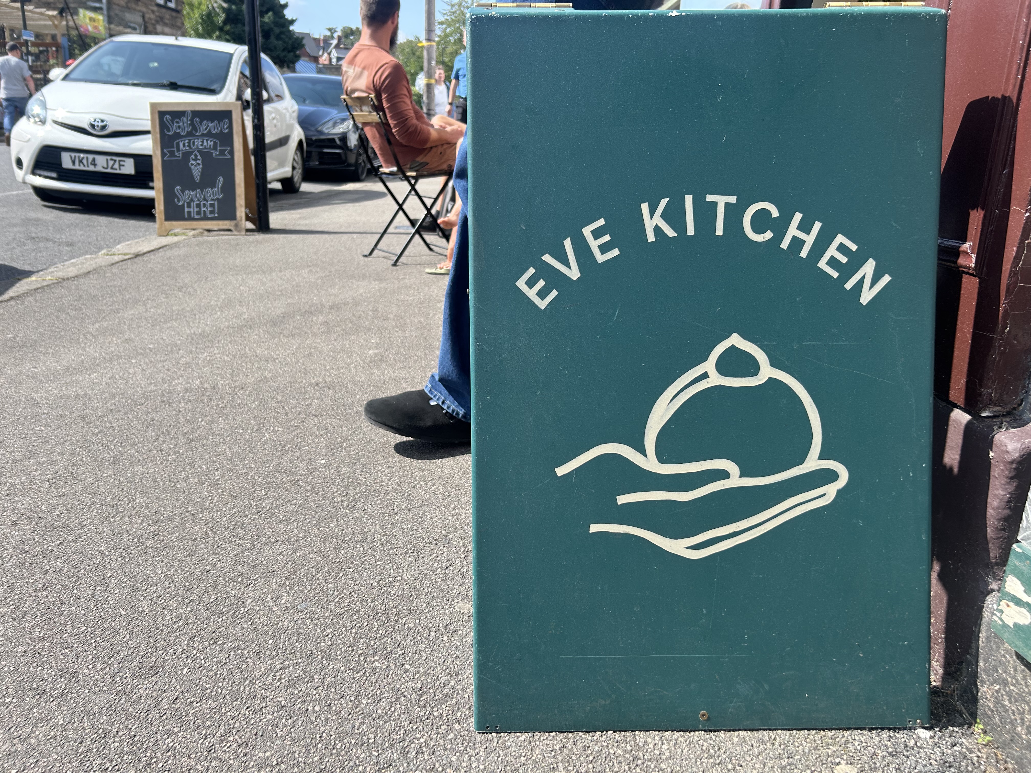 Blue sign with the words Eve Kitchen on it placed in the centre of the sign