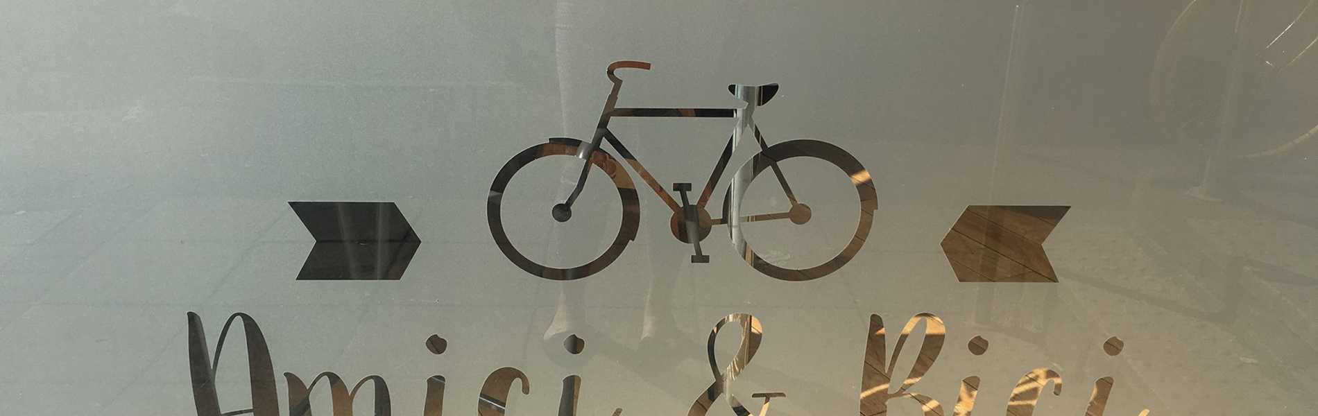 The Amici & Bici logo picked out in frosted glass on the restaurants window.