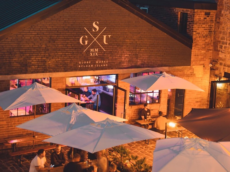 People eating at tables outside Saw Grinders Union at night.