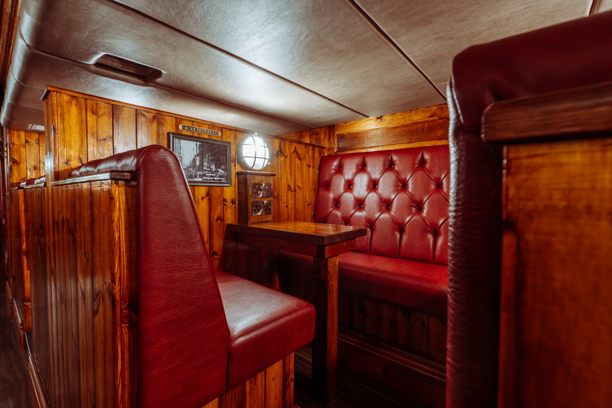 A bar booth with wood panelling and red leather upholstery. 
