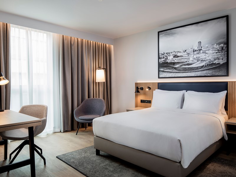 Modern bedroom with a double bed and a local picture hanging on the wall and cool lighting.