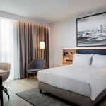 Modern bedroom with a double bed and a local picture hanging on the wall and cool lighting.