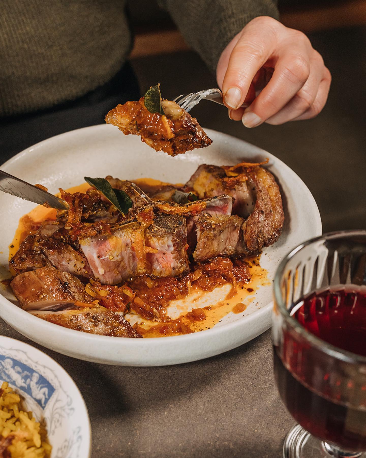 A knife and fork are shown cutting up a joint of slow cooked tender meat in a white dish