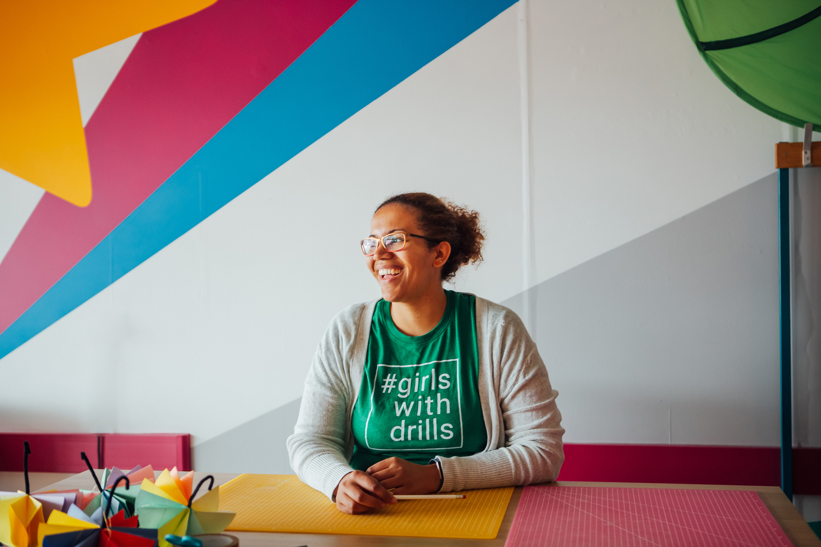 A photo of Kisha Bradley, Founder of Brightbox and Girls with Drills, sat at a desk.