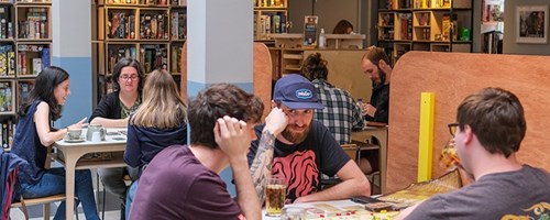 People sat at tables in a cafe, playing board games.
