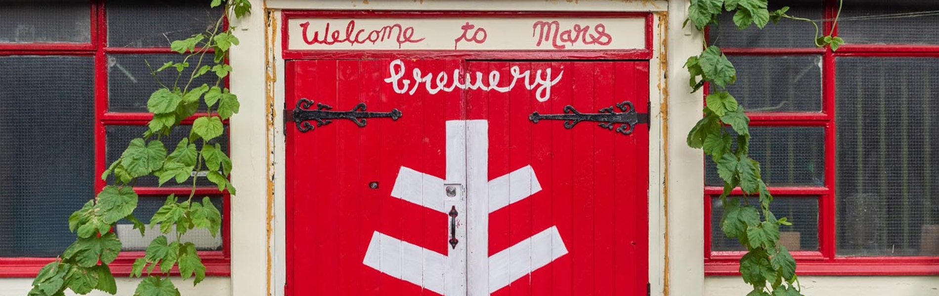 Bright red wooden double doors at The Brewery of St Mars of the Desert.