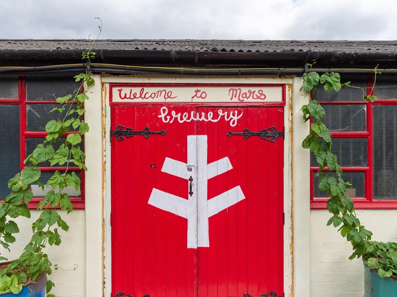 Bright red wooden double doors at The Brewery of St Mars of the Desert.
