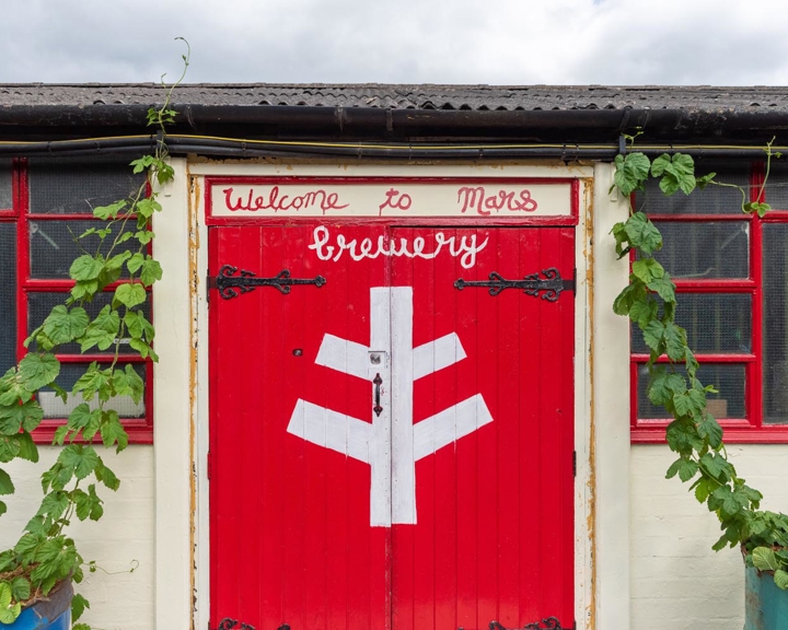 Bright red wooden double doors at The Brewery of St Mars of the Desert.