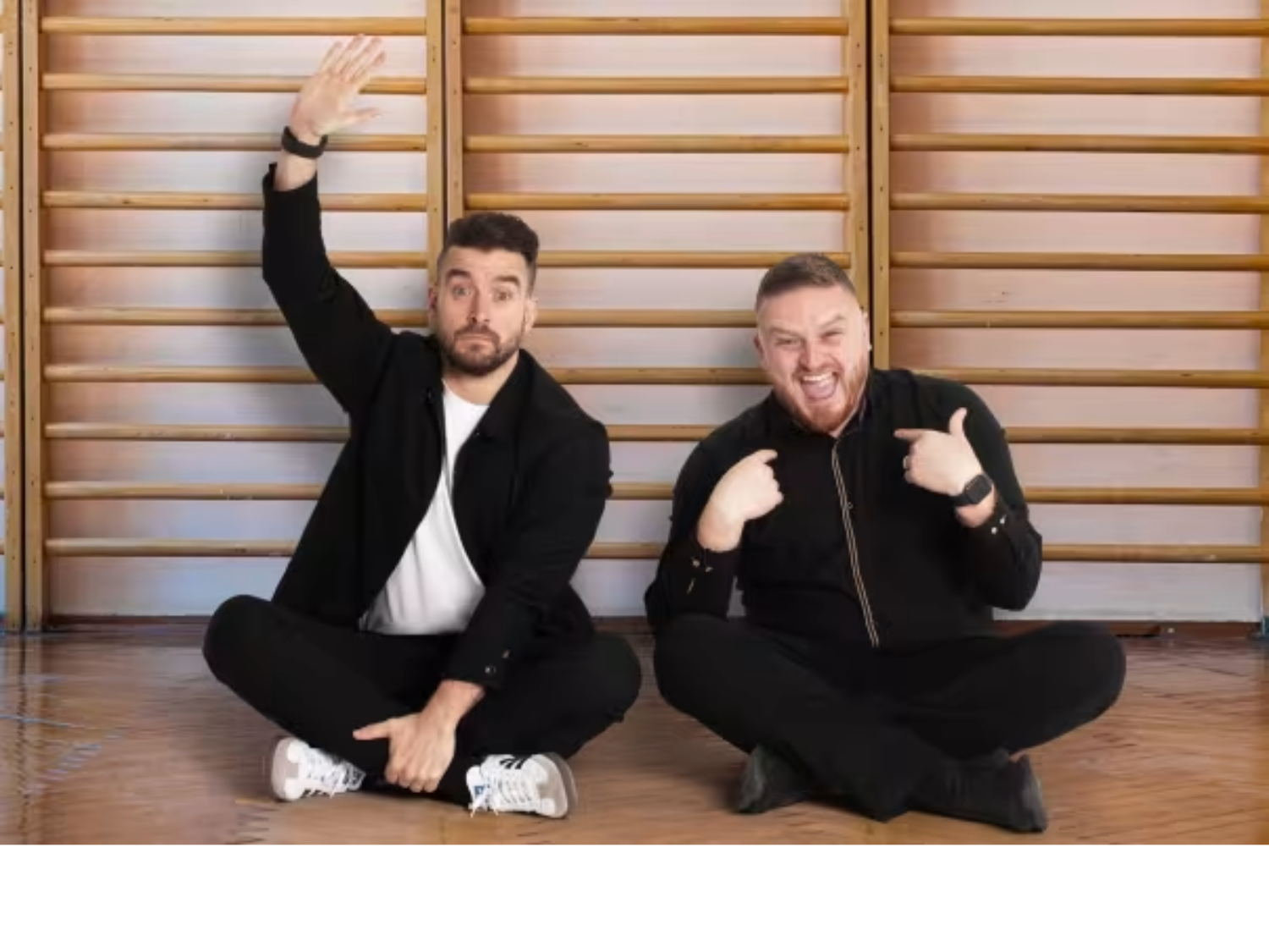 The two Mr Ps are sitting on the floor in a school gym.