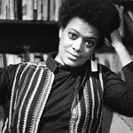 A black and white shot of a person in front of a bookshelf.