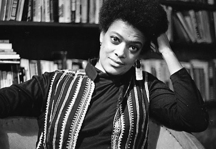 A black and white shot of a person in front of a bookshelf.