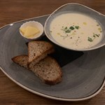 A bowl of soups with some crusty bread.