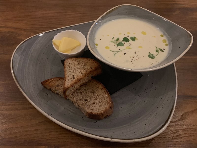 A bowl of soups with some crusty bread.