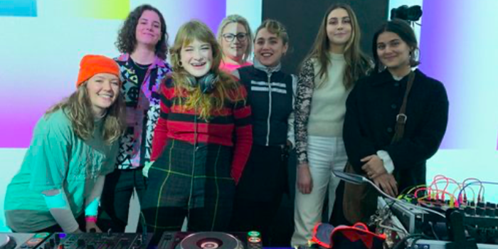 A group of people standing behind DJ decks.