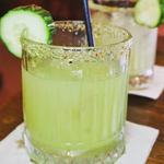 A green cocktails with a slice of lime on the rim at Pellizco