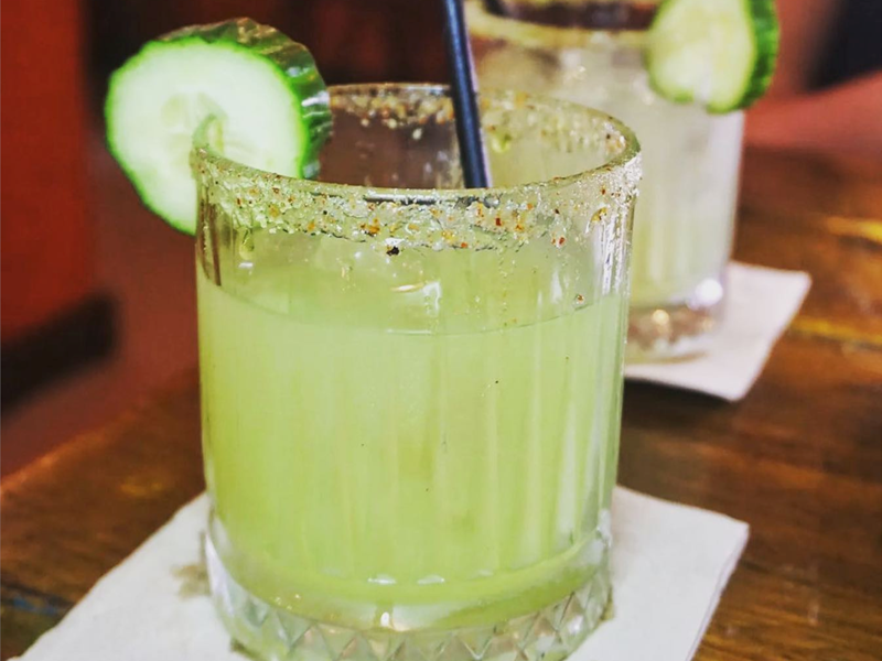 A green cocktails with a slice of lime on the rim at Pellizco