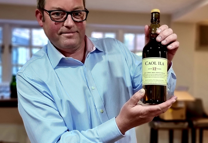 A man holding up a bottle of whiskey.