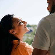 A couple at an open window, looking into each others eyes happily.