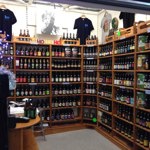 Wooden shop shelving filled with bottles and cans of all different types and brands of beer.