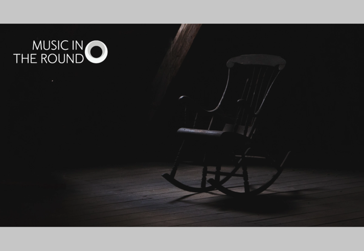 A rocking chair sits empty in a darkened room.