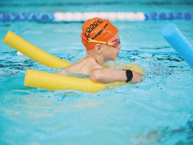 A child learning to swim in a swimming pool.