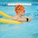 A child learning to swim in a swimming pool.