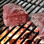 Two steaks on a charcoal grill.
