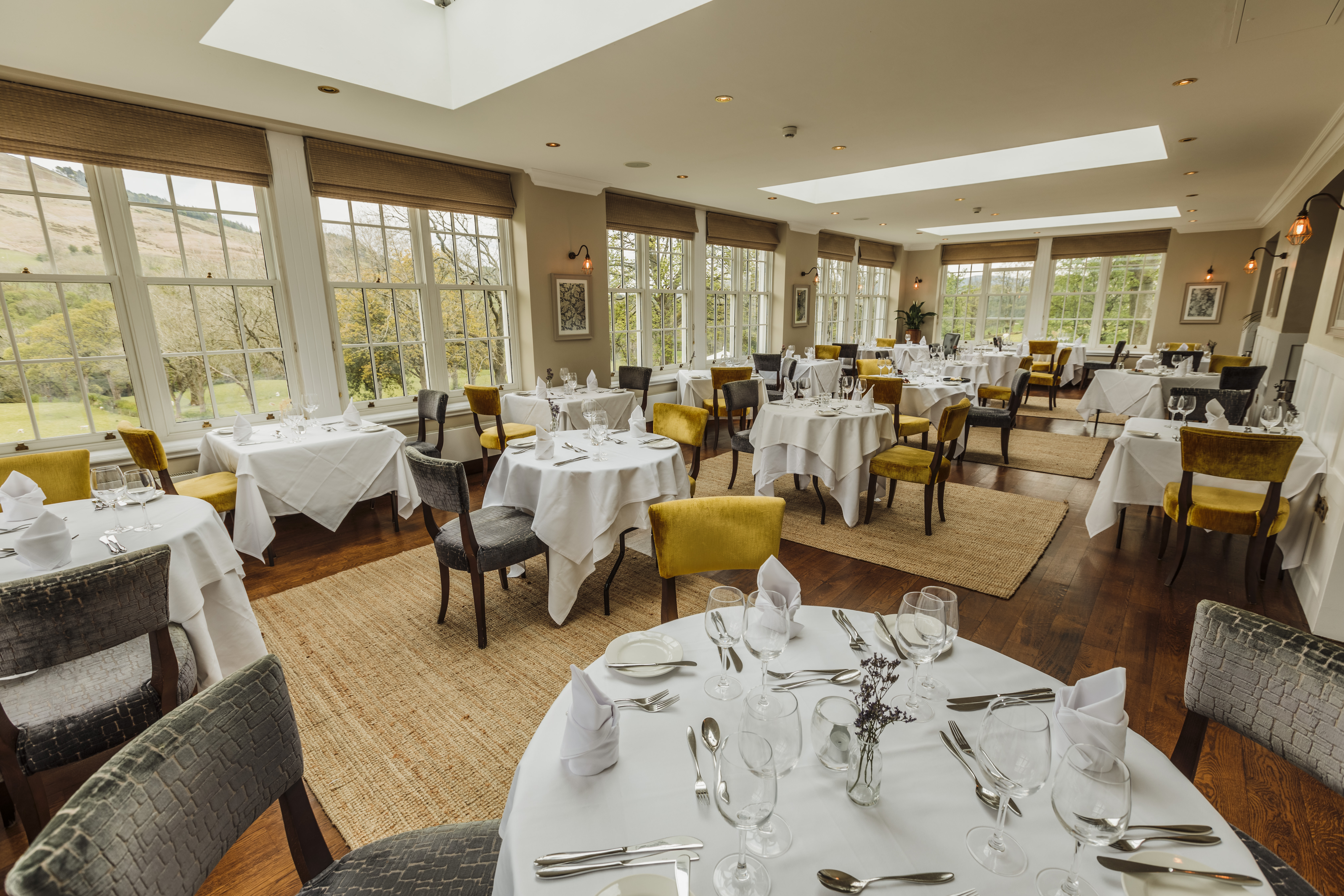 Bright and spacious restaurant with round tables and stylish décor at Losehill House Hotel.