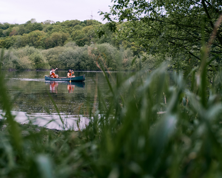 Two people in a kayak paddle across a stretch of water. 