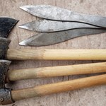 Three throwing axes and three throwing knives on the ground.