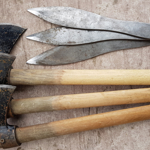Three throwing axes and three throwing knives on the ground.