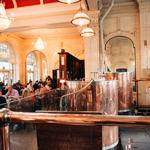 Sheffield Tap copper beer tanks to the right, with groups of people sat down talking and drinking to the left.