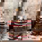 A bass drum lying on its side, on the floor, with a vase of flowers, a decanter and two glasses on top.