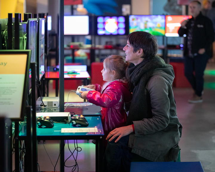 A child sits on their mothers lap, playing a video game at the National Videogame Museum in Sheffield.