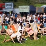 Rows of people sat in deckchairs at an outdoor event.