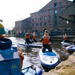 A group of people learning how to do stand-up paddle boarding at Victoria Quays in Sheffield city centre.