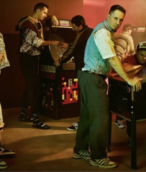 Sumo Digital - 9 men posing around arcade machines.