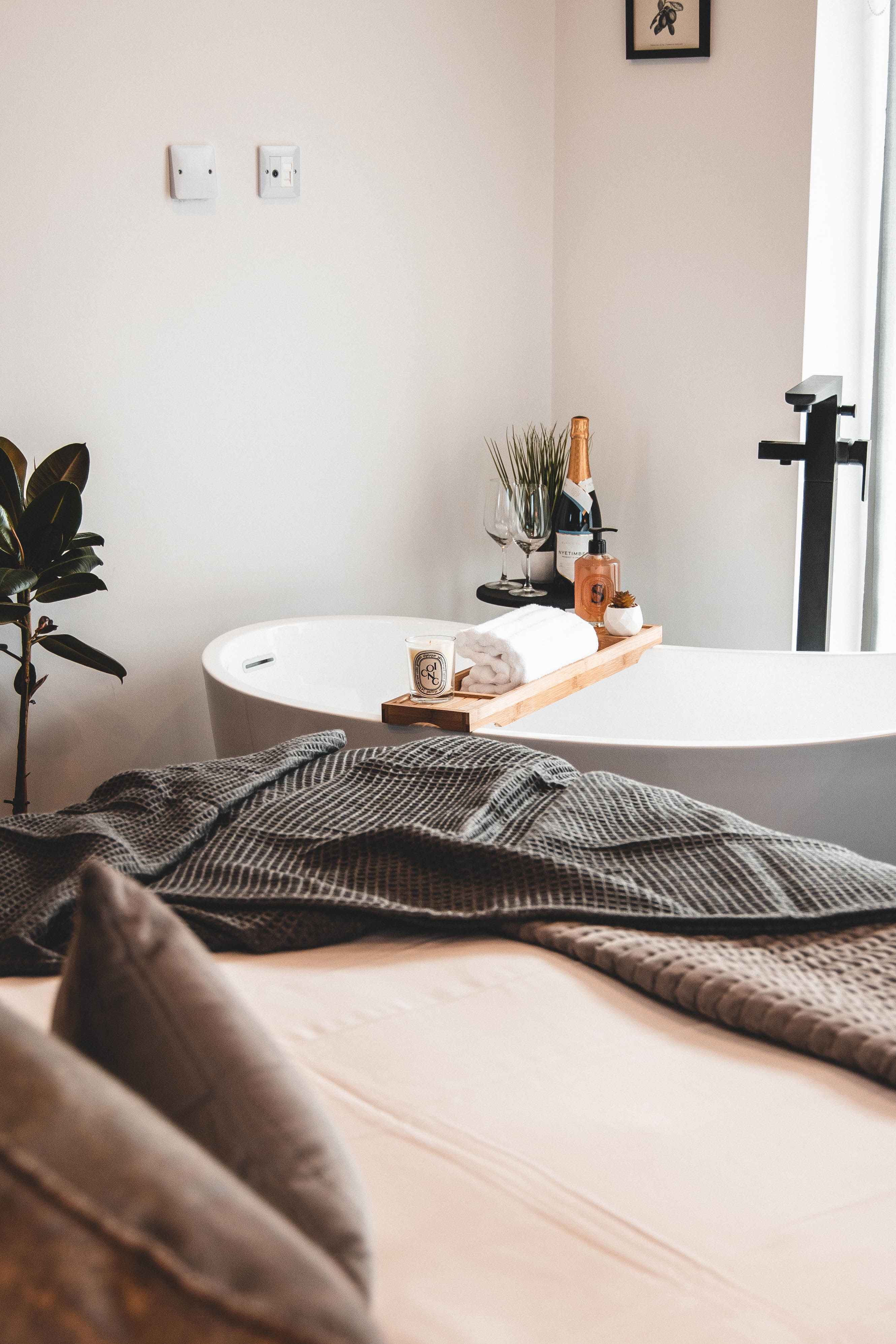 A room at the House Of JÖRO with a double bed in the foreground and a free-standing bath in the background.