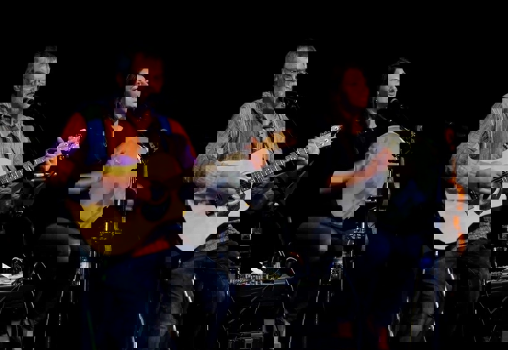 Two people, on stage, playing folk music.