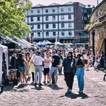 Sunny day as people walk along the cobbled quayside