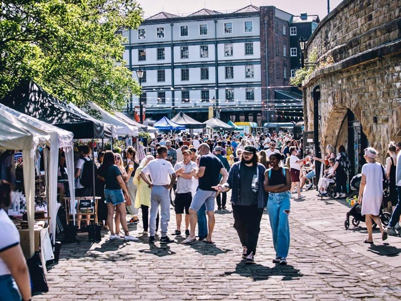 Sunny day as people walk along the cobbled quayside