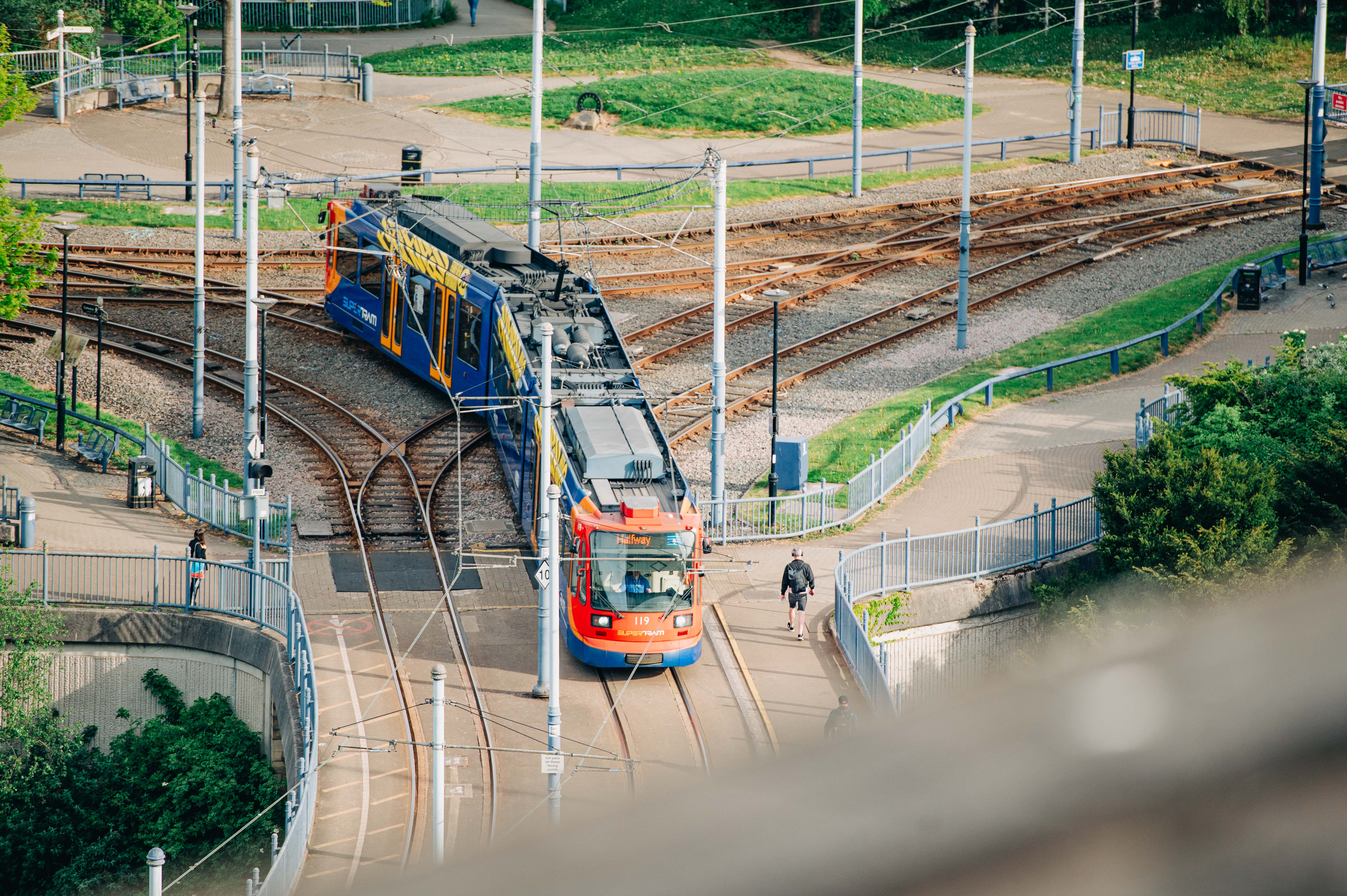 A Sheffield Supertram travelling along curved tracks, seen from above, with rail lines, walkways and greenery surrounding the junction.